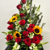 Tall arrangement of red roses, yellow sunflowers, and white snapdragons in a fan-shaped design