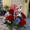 A basket filled with assorted flowers in the shades of red, white