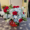 Arrangement designed in a compact glass container with assorted blue hydrangea, hot