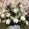 White floral arrangement in a basket with a sheer ribbon bow