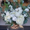 Low woven basket of white roses and hydrangeas with eucalyptus accents for