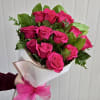 Bouquet of bright pink roses wrapped in white paper with a pink ribbon