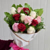 Handheld bouquet of red, pink, and white roses wrapped in white paper