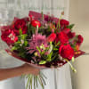 Velvety red roses paired with tulips and a large lavender-pink chrysanthemum-like bloom