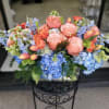 This lush, low-profile arrangement features a sophisticated blend of blush and coral
