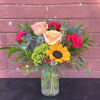 Mixed bouquet with roses, sunflower, and pink carnations in a glass vase