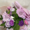 Pink and purple bouquet with chrysanthemums, roses, and carnations wrapped in pastel paper