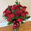 Classic red roses paired with vibrant red carnations and fresh greenery create