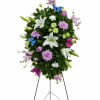 A graceful standing spray of white lilies, lavender blooms, and lush greenery