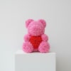 A whimsical teddy bear sculpted entirely from tightly packed pink roses with