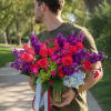 Vivid magenta roses and towering purple stock give this flower arrangement an