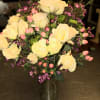 Yellow roses in a clear glass vase with pink filler flowers