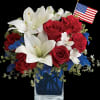 Red roses and white lilies in a blue vase with a small American flag