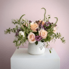 Peach roses and purple flowers in a white vase