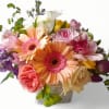 Colorful bouquet of peach gerbera daisies, roses, and mixed blooms in a small textured container