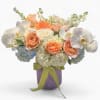 Peach and white mixed flower arrangement in a lavender vase with green ribbon
