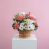 Pink roses and white daisies arranged in a charming wicker basket. A