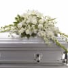 Pure white lilies take center stage in this sympathy spray, creating a