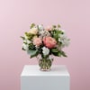 Soft pink and white blooms arranged in a clear glass vase. A