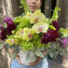 Bouquet of yellow orchids and dark purple flowers in a white vase