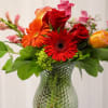 Mixed bouquet of red roses and gerbera daisies in a textured glass vase