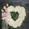 Heart-shaped white floral wreath with pink roses and a white ribbon bow