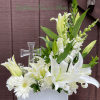 A serene, upright sympathy arrangement centered on pure white lilies and a