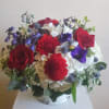 Upscale red, white and blue blooms designed in a white container or