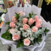 Bouquet of pink roses with white filler flowers wrapped in white paper