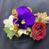 Floral wrist corsage with purple pansy, red rose, and succulents