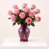 Pink roses arranged in a purple glass vase