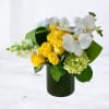 Yellow roses and white orchids arranged in a dark green vase