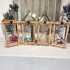 Four wooden lanterns with floral prints and small purple flower arrangements