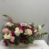 Lush blush roses and bold pink gerbera daisies spill from a rustic