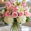 Soft pink roses and airy white lilies combine with ruffled carnations and