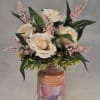 Cream roses and pink filler flowers arranged in a candle jar