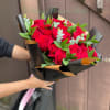 A dense cluster of red roses bundled in a rounded hand-tied form