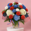 Red, white &amp; blue hydrangeas and carnations in a clear glass vase