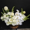 A serene low centerpiece of white phalaenopsis orchids, calla lilies, and anthuriums