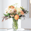 Peach and white flowers arranged in a clear glass vase