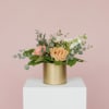 Peach and pink rose arrangement in a gold cylinder vase
