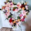 Heart-shaped floral wreath on a stand with pink, white, red, and orange flowers