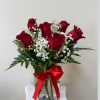Red roses in a glass vase with baby's breath and a red ribbon