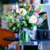 Mixed bouquet of pastel flowers in a glass vase with a ribbon