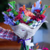 Colorful bouquet with pink, purple, and orange flowers wrapped in paper