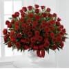 A lush dome of deep red roses crowns a white ceramic vase