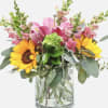 Bouquet of sunflowers and pink flowers in a clear glass vase