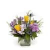 Mixed bouquet of yellow roses and purple flowers in a clear glass cube vase