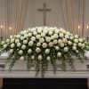 A full cascade of pure white roses creates a serene, reverent tribute-perfect