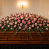 A large, full casket spray of pink roses creates a tender, respectful